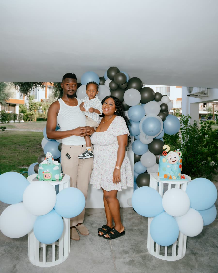 Familia posando junto a un arco de globos y pasteles en el cumpleaños de un niño