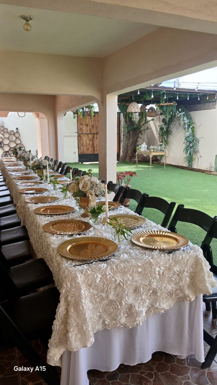 Mesa larga con mantel bordado y vajilla dorada servida para un banquete